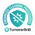 A badge with a shield icon in the center, showing a sparkling symbol divided by a diagonal line. The text around the shield reads "Enhanced Cleaning Procedures," and below the badge, the logo reads "TurnoverBnB".